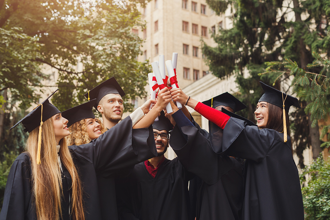 Group of multiethnic graduate students celebrating by cheering with their diplomas. Education, qualification and graduation concept.